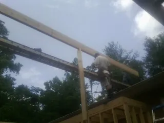 Carpenter setting a ridge beam over a new addition frame — Ice Dam Removal by Roofing Brothers in Tuckasegee