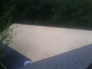 New OSB roof sheathing installed beside an existing shingle roof in Tuckasegee