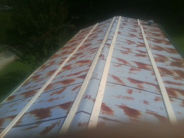 Rusted metal roof panels with new wood purlins before replacement — Storm Damage Roof Repair in Tuckasegee by Roofing Brothers