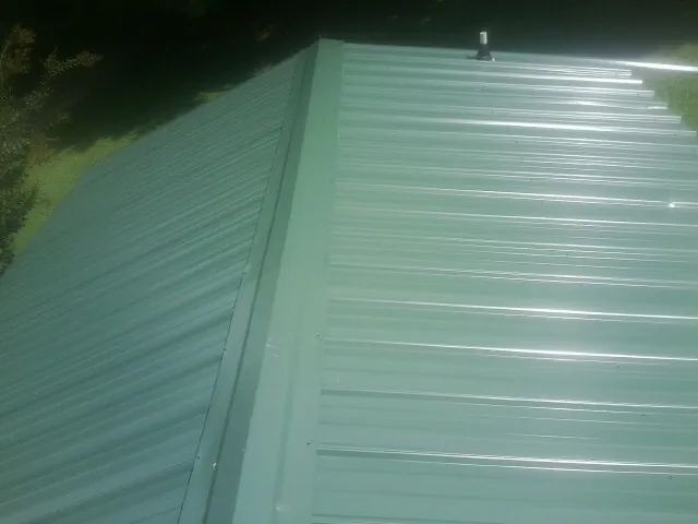 New green metal panels meeting at the ridge of a roof — Flat Roof Repair work by our crew in Tuckasegee