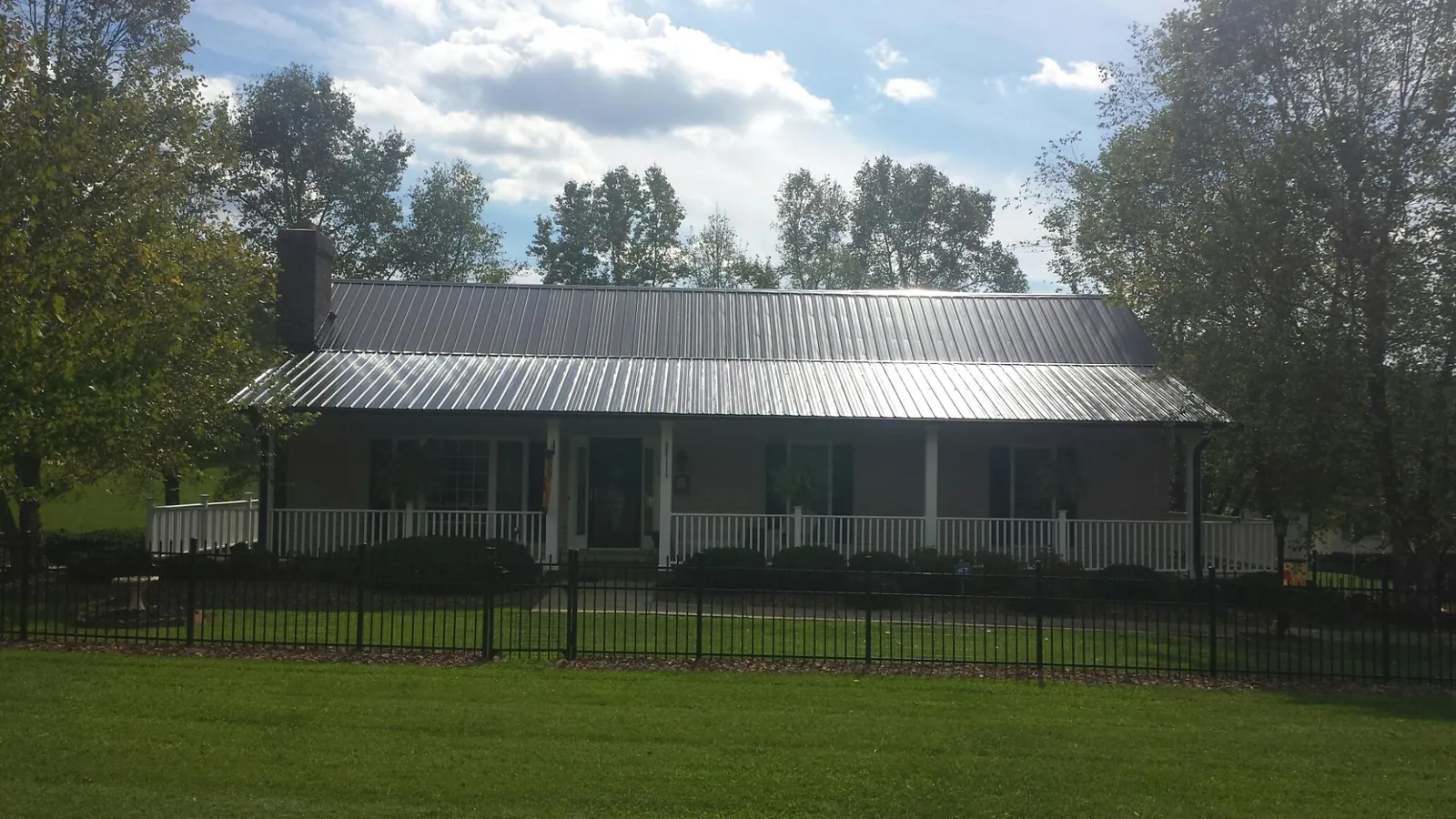 Gray metal roof on a brick ranch with a full width front porch — Gutter Guard Installation work by our crew in Tuckasegee