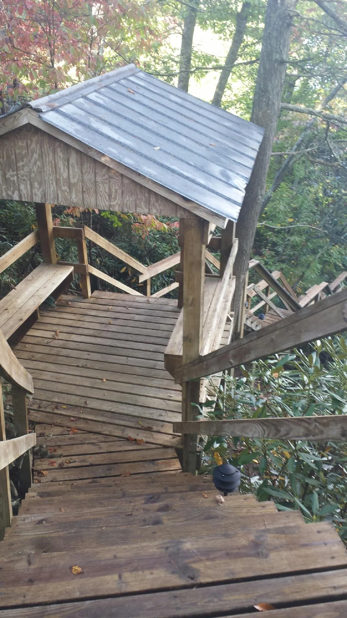 Metal roofed shelter over wooden steps on a wooded walkway — Skylight Repair & Installation work by our crew in Tuckasegee