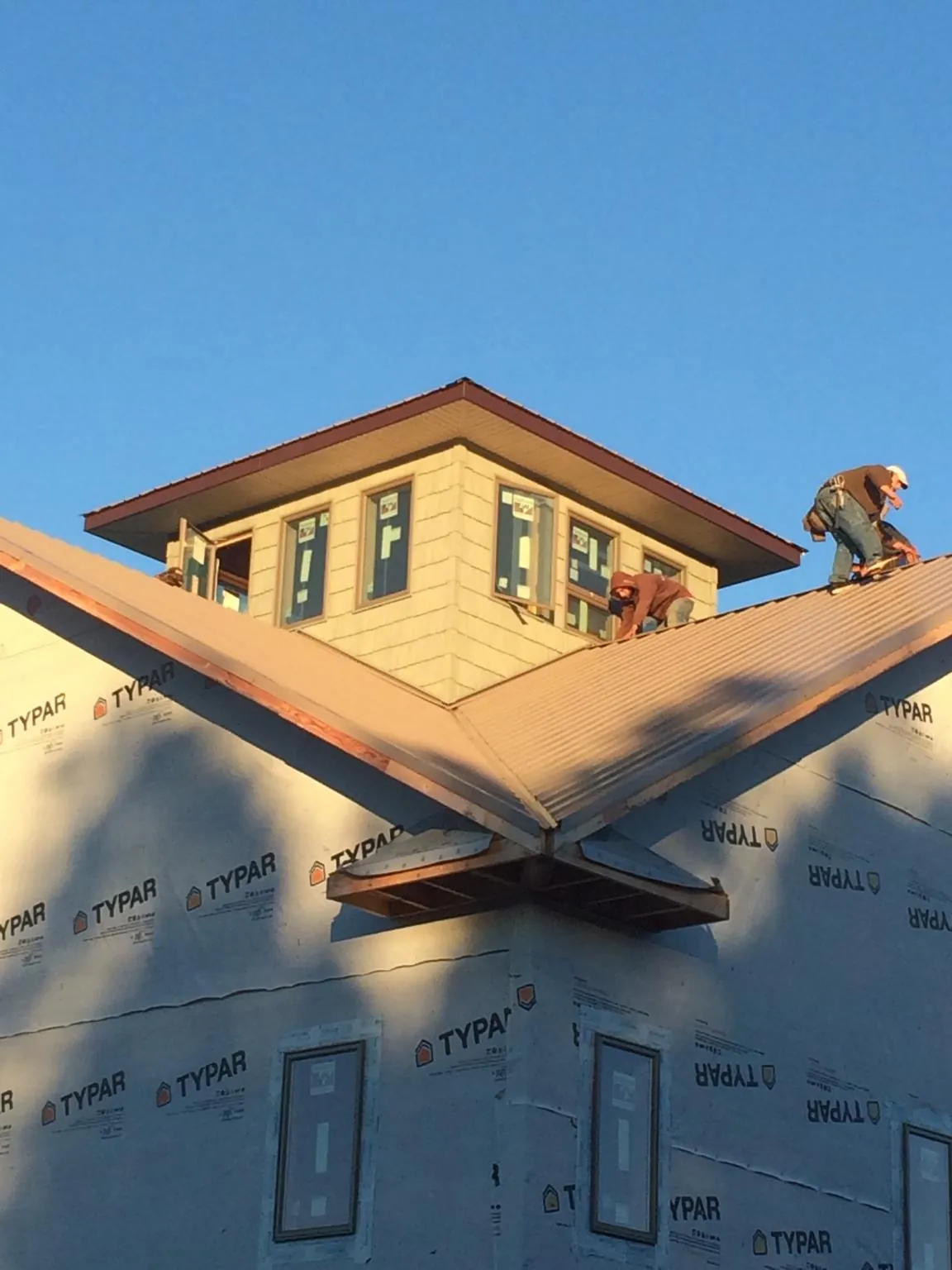 Roofers working around a rooftop cupola on a new metal roof at sunset — Roof Waterproofing in Tuckasegee by Roofing Brothers
